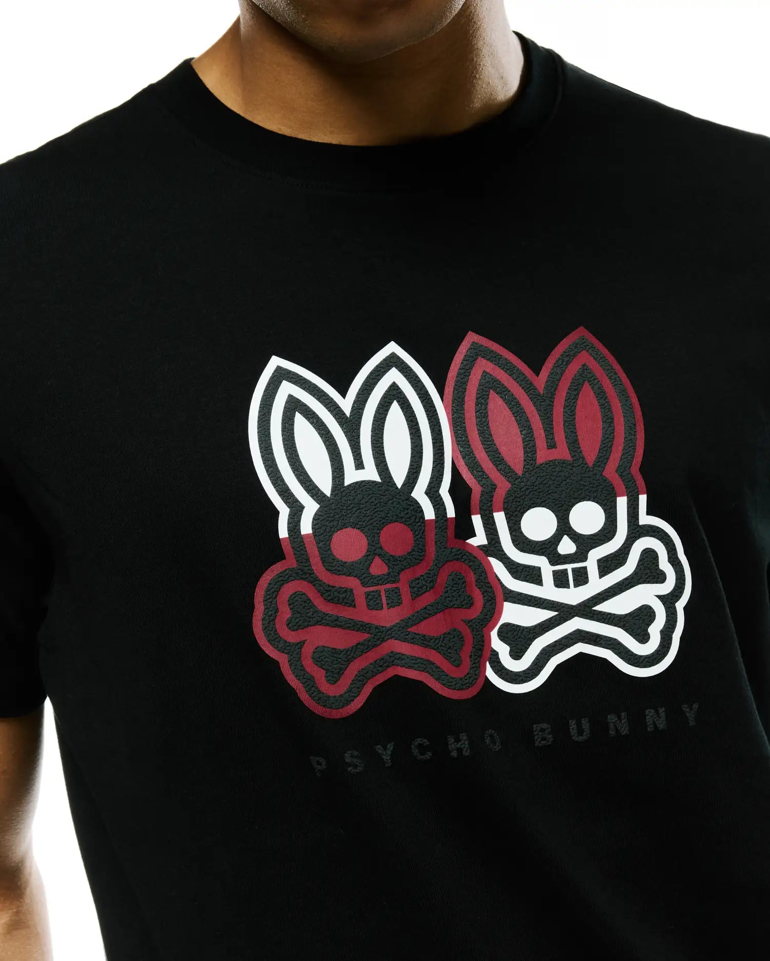 Mens Ledger Graphic Tee, a black jersey knit t-shirt with a classic fit, featuring a large textured chest graphic of two Psycho Bunny skull logos, one red and black, one white and black, with Psycho Bunny text below.