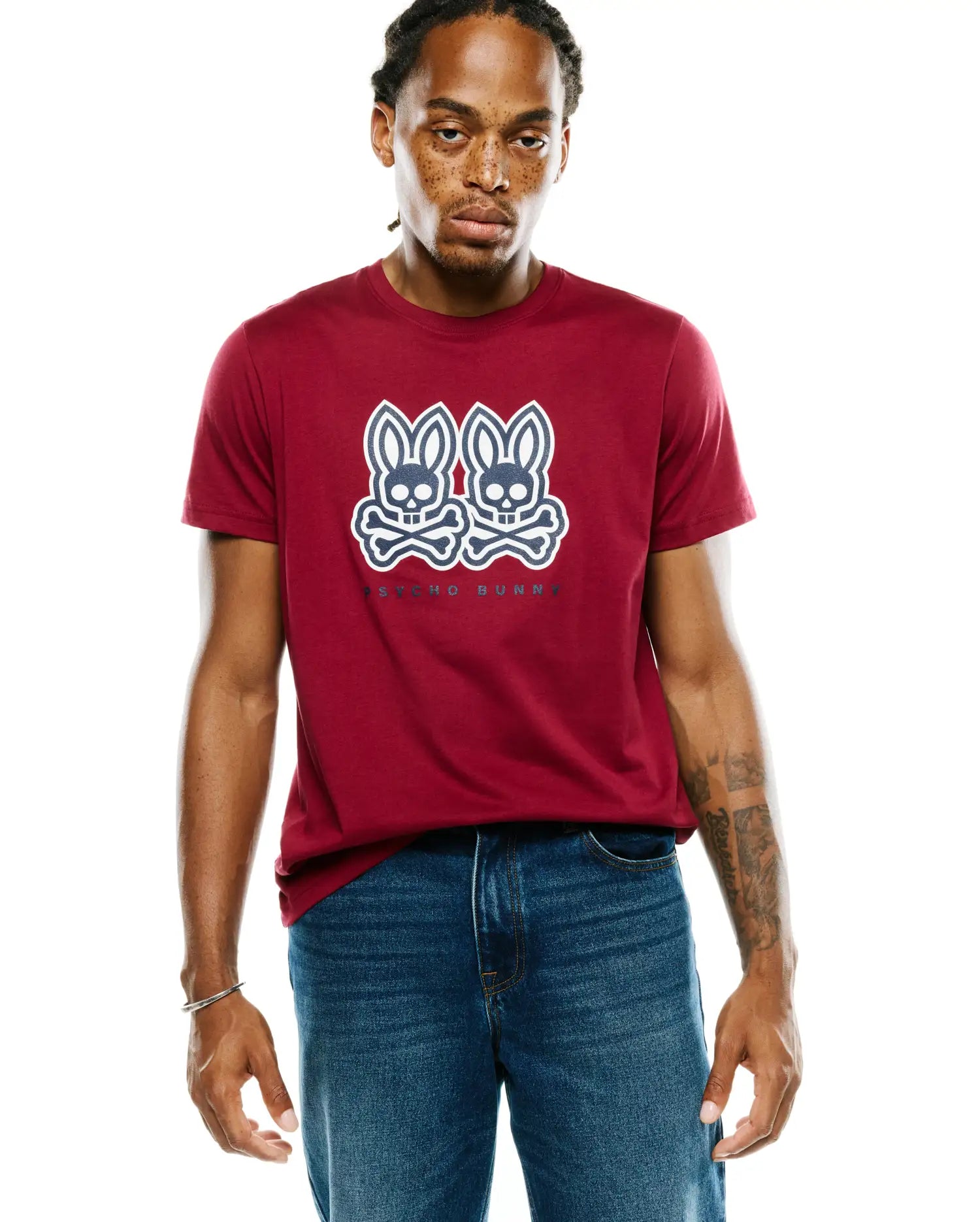 Mens Ledger Graphic Tee, a classic fit maroon jersey t-shirt with a large white and dark blue Psycho Bunny skull and crossbones graphic print on the center chest.