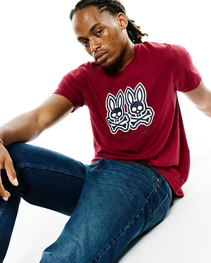 Mens Ledger Graphic Tee in maroon, a classic fit soft jersey knit t-shirt featuring a large white and dark blue Psycho Bunny skull and crossbones graphic on the chest.