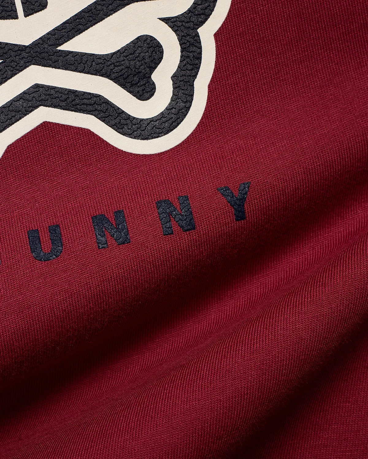 Mens Ledger Graphic Tee in rich burgundy jersey knit, featuring a large textured dark grey and cream Psycho Bunny skull logo graphic with UNNY text on the chest.
