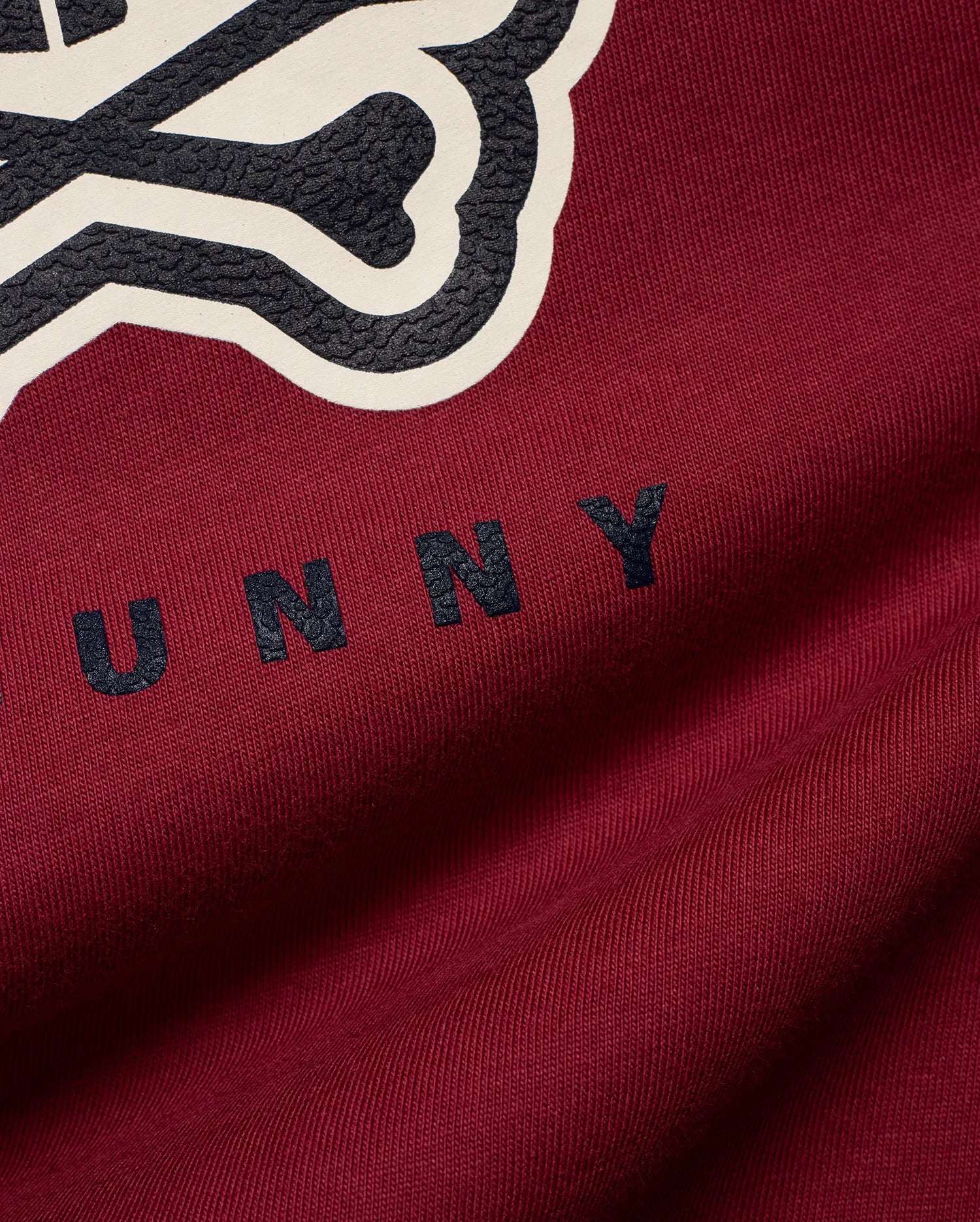 Mens Ledger Graphic Tee in rich burgundy jersey knit, featuring a large textured dark grey and cream Psycho Bunny skull logo graphic with UNNY text on the chest.