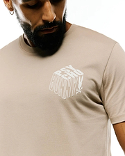Mens Conan Back Graphic Tee, a classic fit light beige jersey t-shirt with a prominent white 3D block Psycho Bunny text graphic and skull logo on the chest.
