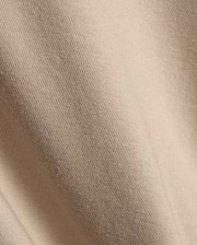 Psycho Bunny Mens Conan Back Graphic Tee in a warm, light beige, showcasing the refined, soft diagonal ribbed knit jersey fabric texture, characteristic of premium streetwear.
