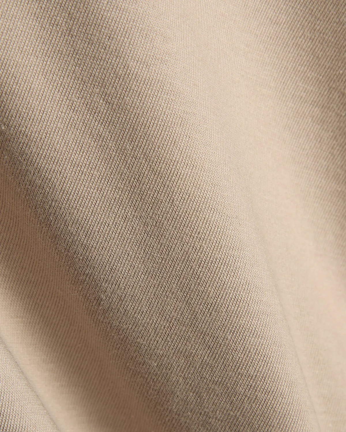Psycho Bunny Mens Conan Back Graphic Tee in a warm, light beige, showcasing the refined, soft diagonal ribbed knit jersey fabric texture, characteristic of premium streetwear.