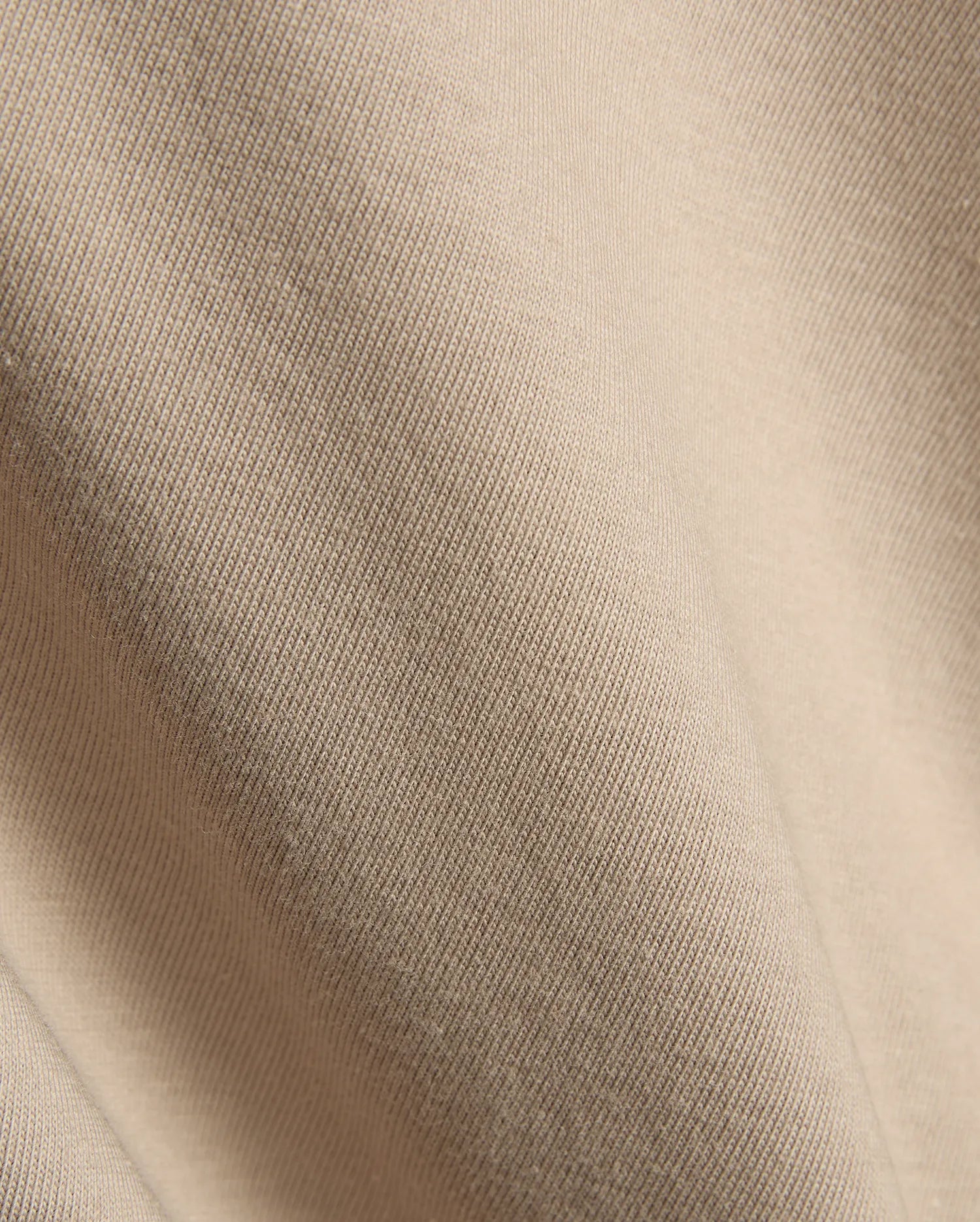 Psycho Bunny Mens Conan Back Graphic Tee in a warm, light beige, showcasing the refined, soft diagonal ribbed knit jersey fabric texture, characteristic of premium streetwear.