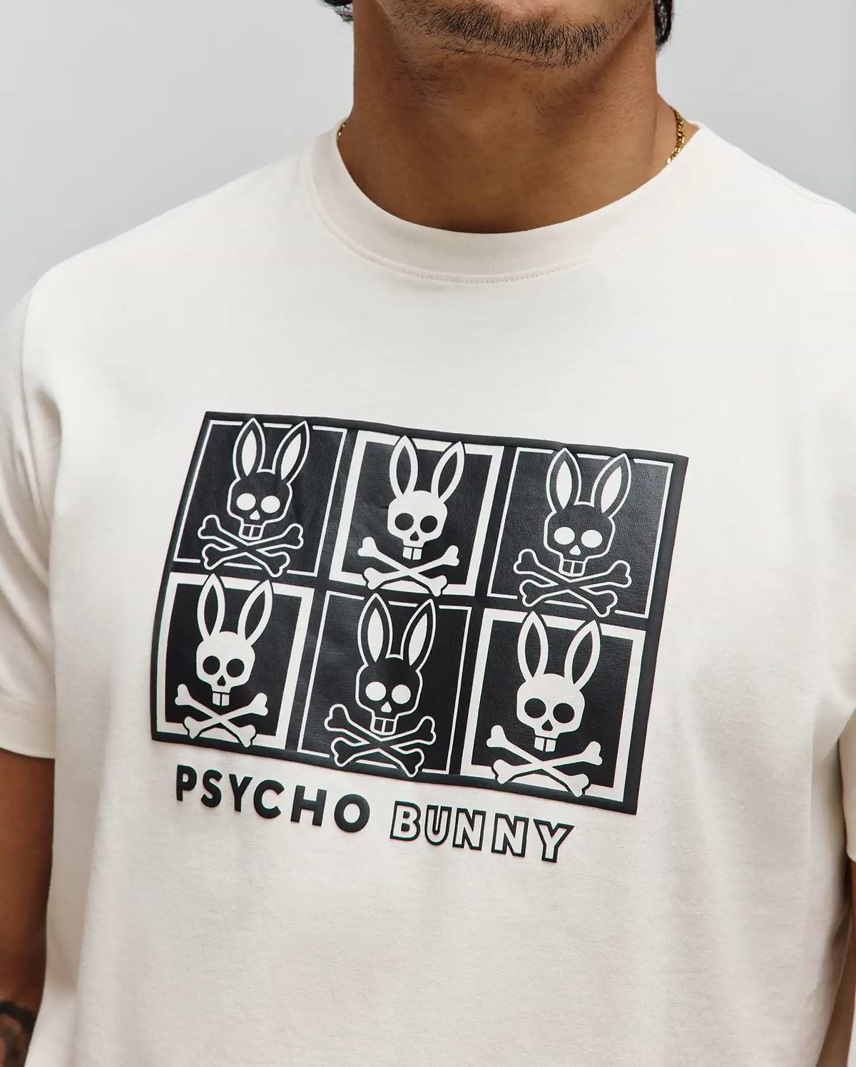 Mens Keon Graphic Tee, cream classic fit jersey knit with a large black and white chest graphic of six Psycho Bunny skull logos in a grid, featuring Psycho Bunny text.