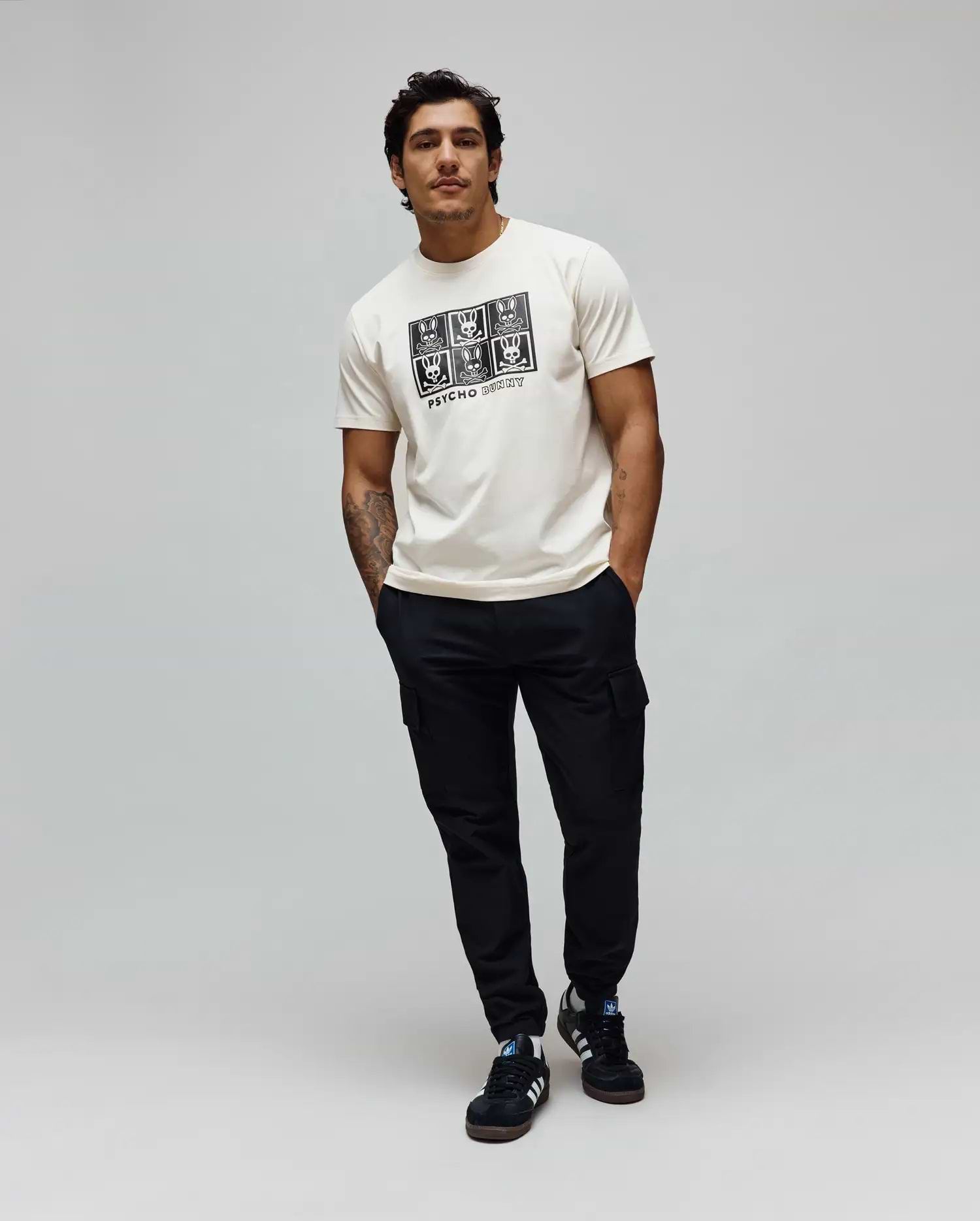 Mens Keon Graphic Tee, ecru classic fit jersey t-shirt with a large black chest graphic featuring a grid of Psycho Bunny skull logos and Psycho Bunny text.
