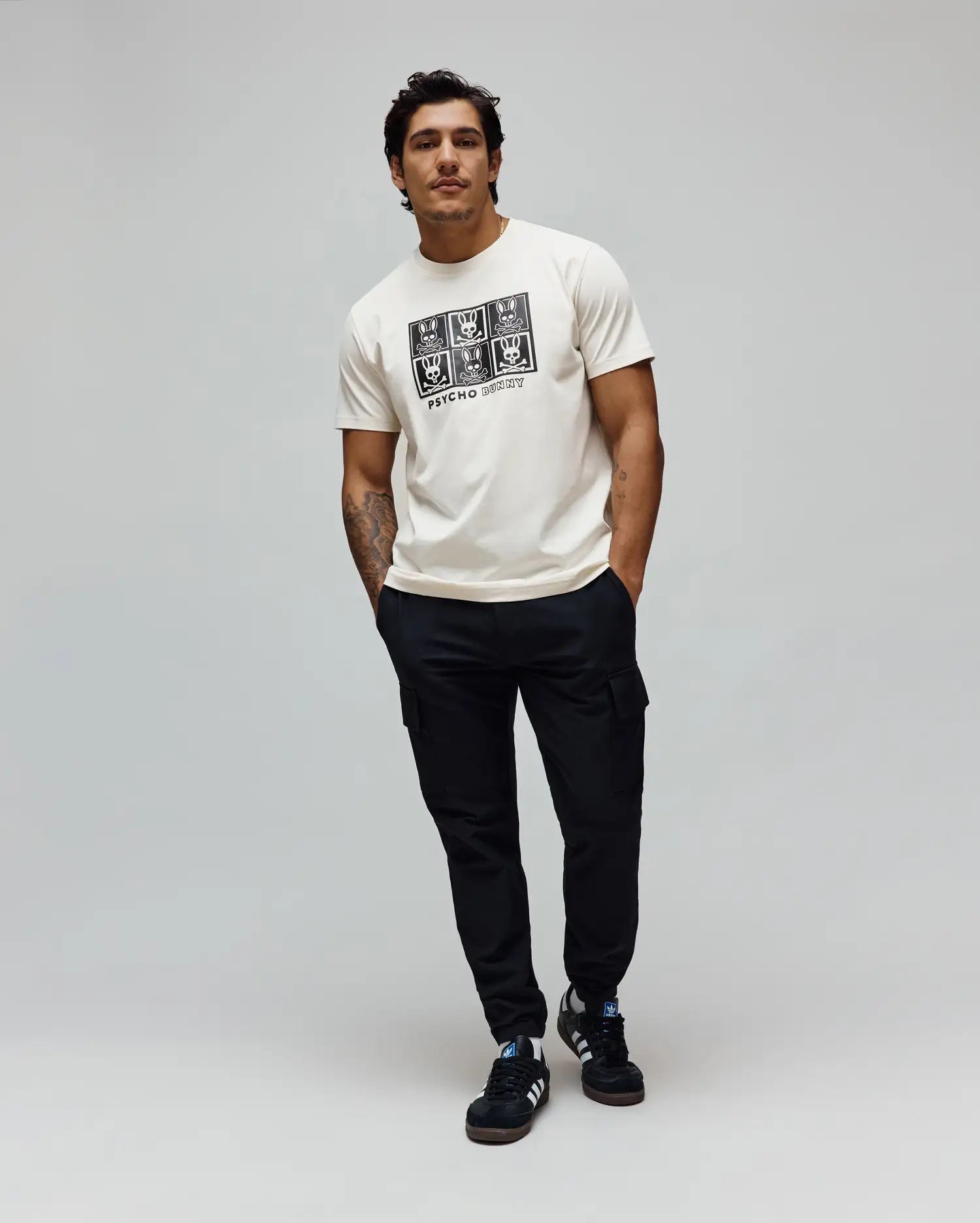 Mens Keon Graphic Tee, ecru classic fit jersey t-shirt with a large black chest graphic featuring a grid of Psycho Bunny skull logos and Psycho Bunny text.