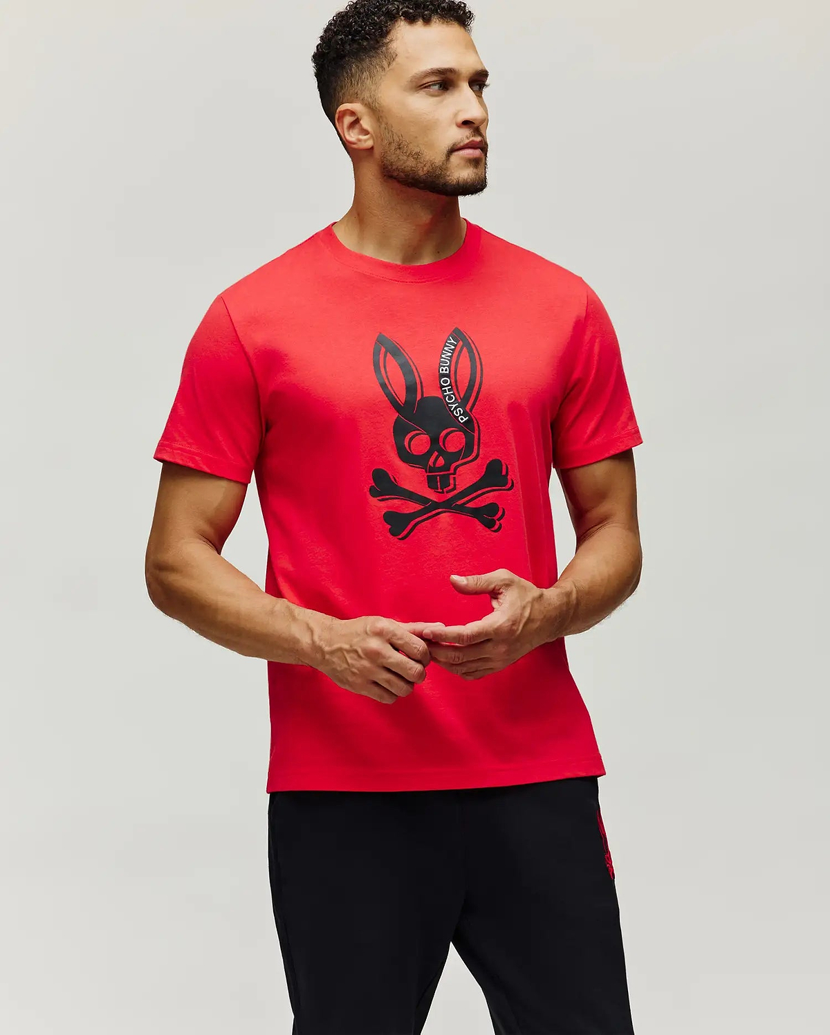 Mens Serge Embroidered Bunny Graphic Tee in vibrant red, featuring a classic fit and a large central black bunny skull and crossbones graphic with Psycho Bunny text on the ear.