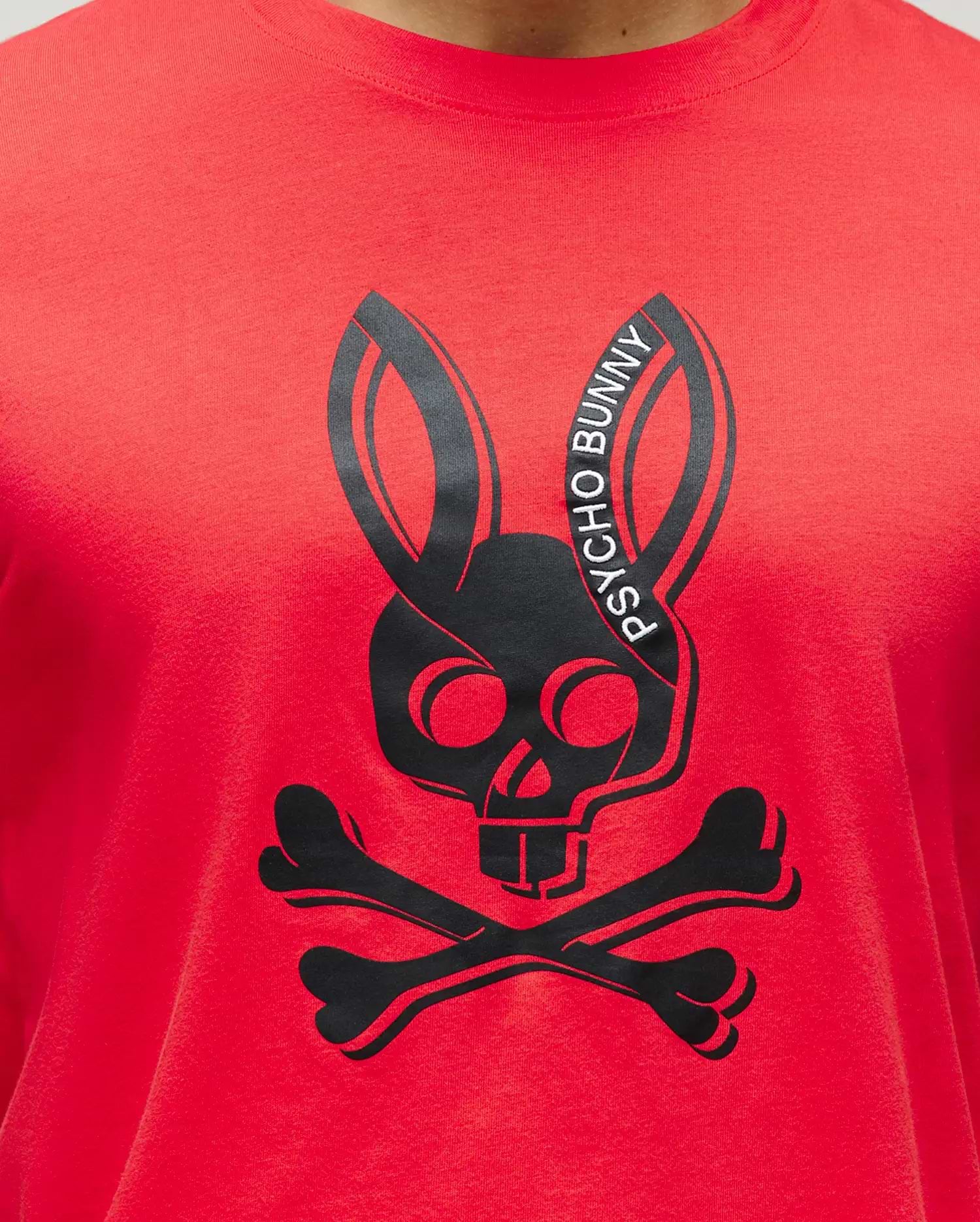 Mens Serge Embroidered Bunny Graphic Tee. A vibrant red classic fit jersey t-shirt featuring a large central black Psycho Bunny skull and crossbones graphic with white Psycho Bunny text.
