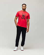 Mens Serge Embroidered Bunny Graphic Tee: Vibrant red classic fit jersey t-shirt featuring a large central black Psycho Bunny skull and crossbones graphic with vertical brand text on the ear.