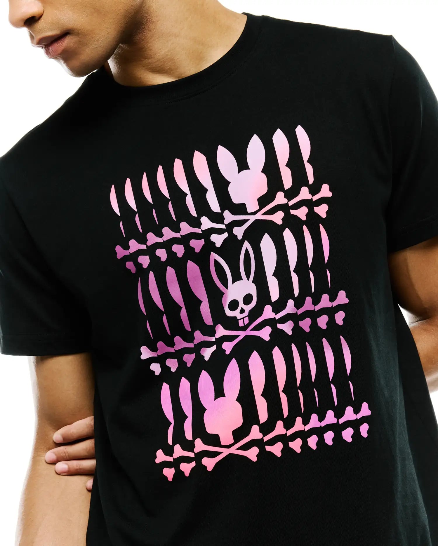 Mens Lewis Graphic Tee, a black classic fit jersey t-shirt featuring a large central pink gradient Psycho Bunny skull and crossbones graphic print in a repeated pattern.