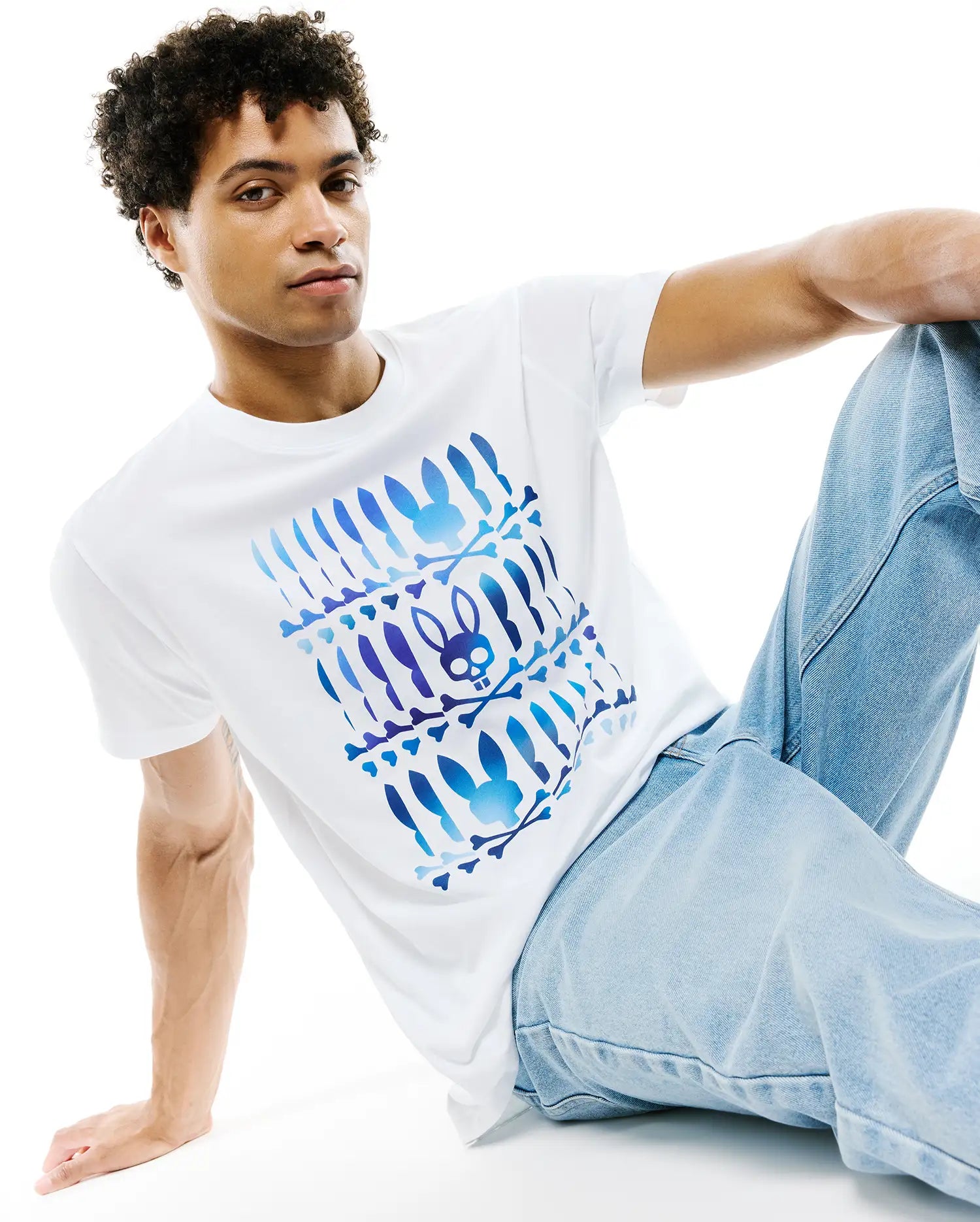 White Mens Lewis Pima Cotton Graphic Tee, classic fit, smooth jersey, with a large central blue and purple gradient Psycho Bunny skull and crossbones graphic pattern.