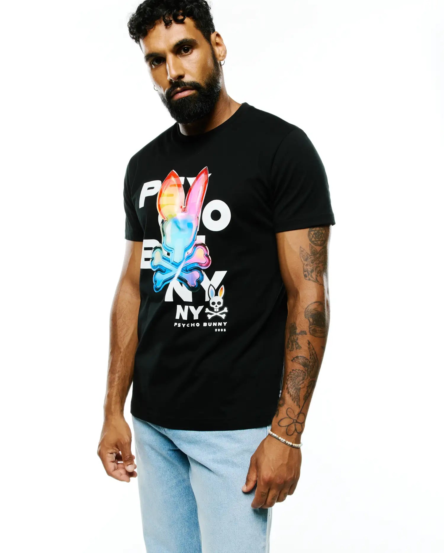 Mens Kenji Pima Cotton Graphic Tee, black classic fit jersey t-shirt featuring a large, vibrant rainbow-colored Psycho Bunny skull graphic on the chest with white PSYCHO BUNNY NY text and a small bunny skull logo.