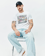 White Mens Byron Graphic Tee with a large central graphic print of colorful Psycho Bunny skull logos and PSYCHO BUNNY text, paired with a black cap featuring a small pink embroidered Psycho Bunny logo. (4)