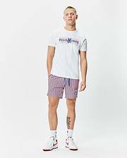 White Mens John Back Graphic Tee with a large layered blue and red Psycho Bunny text and skull logo on the chest, paired with white, red, and blue striped shorts featuring a small embroidered bunny skull logo on the left leg.