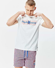 Mens John Back Graphic Tee, a white jersey t-shirt with a large layered red and blue Psycho Bunny chest graphic, paired with red, white, and blue striped shorts featuring a small embroidered bunny skull logo.