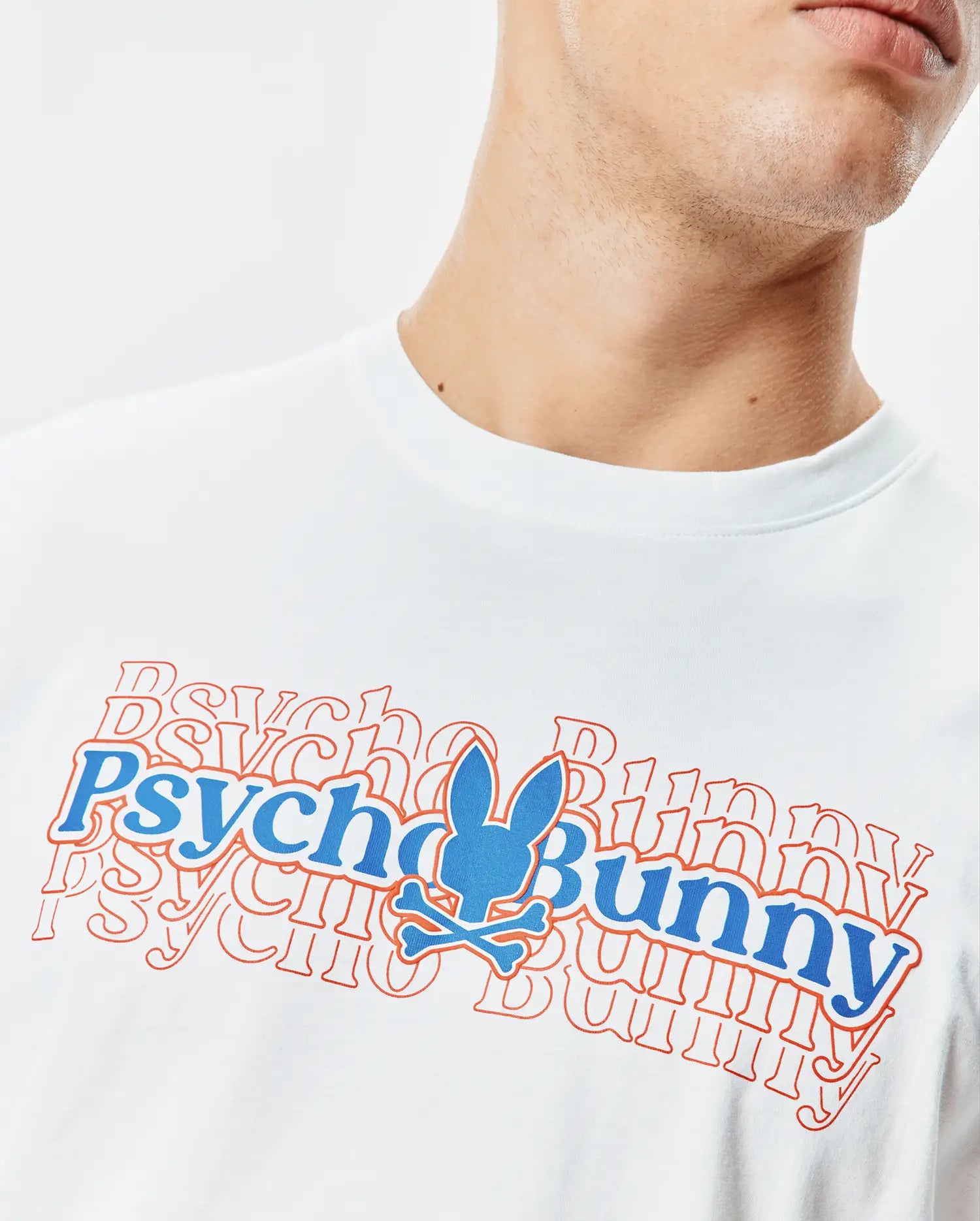 White Mens John Back Graphic Tee, a classic fit jersey t-shirt featuring a large central blue and orange Psycho Bunny text graphic with a layered effect and the iconic bunny skull logo.