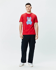 Mens John Graphic Tee. Vibrant red classic fit jersey t-shirt featuring a prominent, centered Psycho Bunny skull logo graphic in white and blue, embodying refined streetwear style.