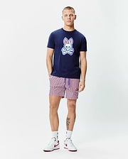 Mens John Graphic Tee, a navy blue jersey t-shirt with a large red, white, and light blue Psycho Bunny skull logo on the chest, paired with red, white, and navy striped shorts featuring a small embroidered bunny logo.