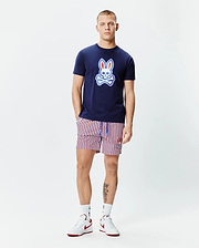 Mens John Graphic Tee, a navy blue jersey t-shirt with a large red, white, and light blue Psycho Bunny skull logo on the chest, paired with red, white, and navy striped shorts featuring a small embroidered bunny logo.