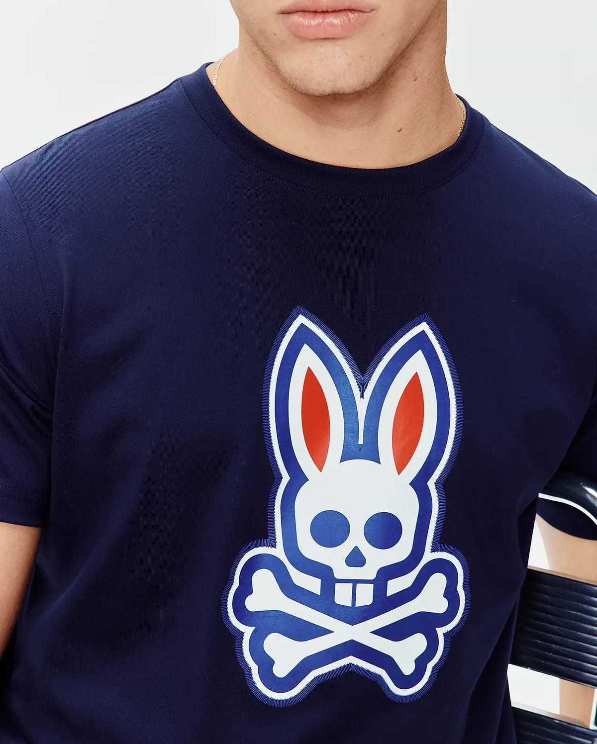 Mens John Graphic Tee, a navy blue classic fit jersey knit t-shirt featuring a large central chest graphic of the iconic Psycho Bunny skull logo in white, blue, and red with an embroidered outline.