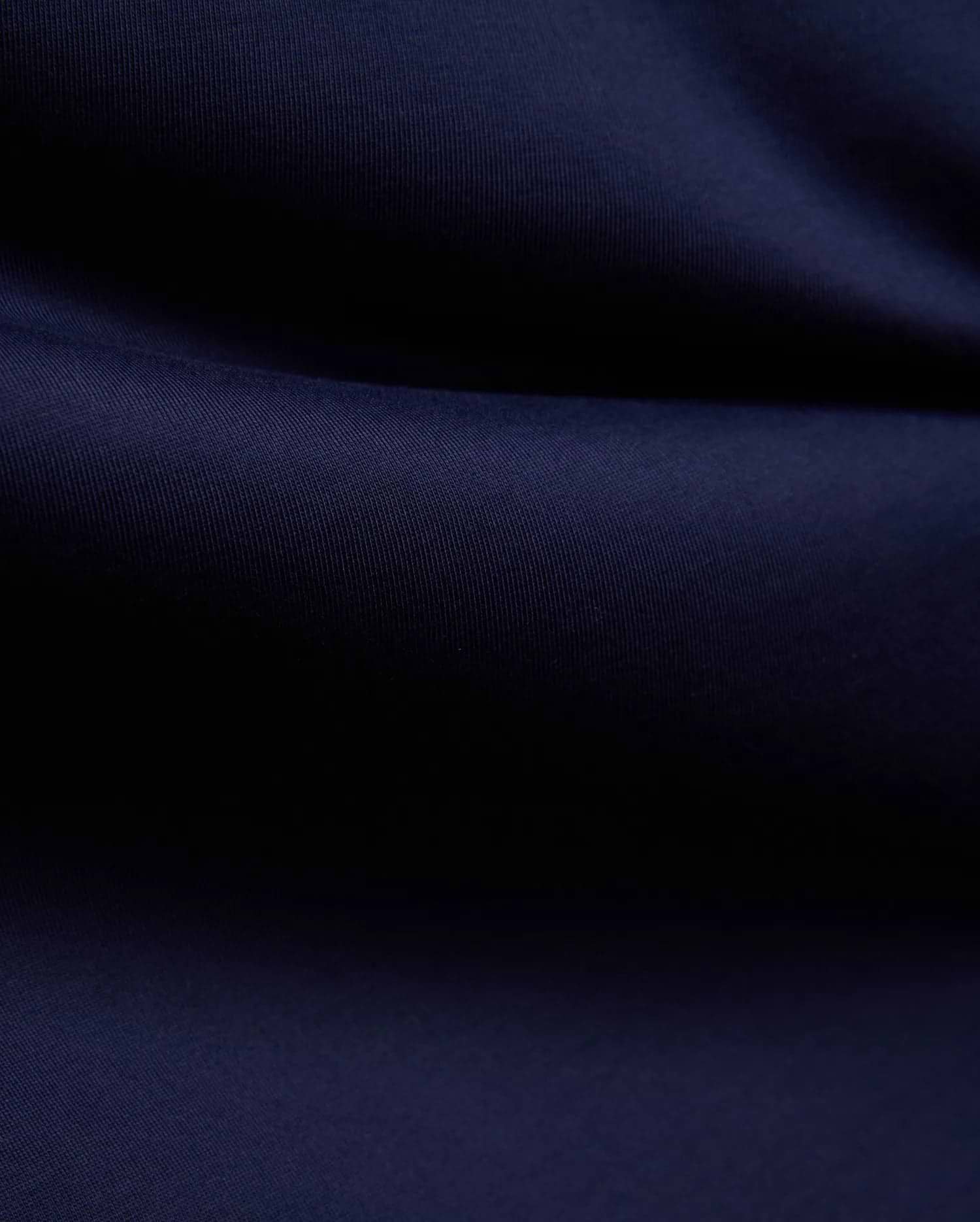 Mens John Graphic Tee, a premium Psycho Bunny dark navy blue t-shirt, showcasing its refined, soft, finely textured jersey knit fabric with elegant, flowing folds, perfect for refined streetwear.