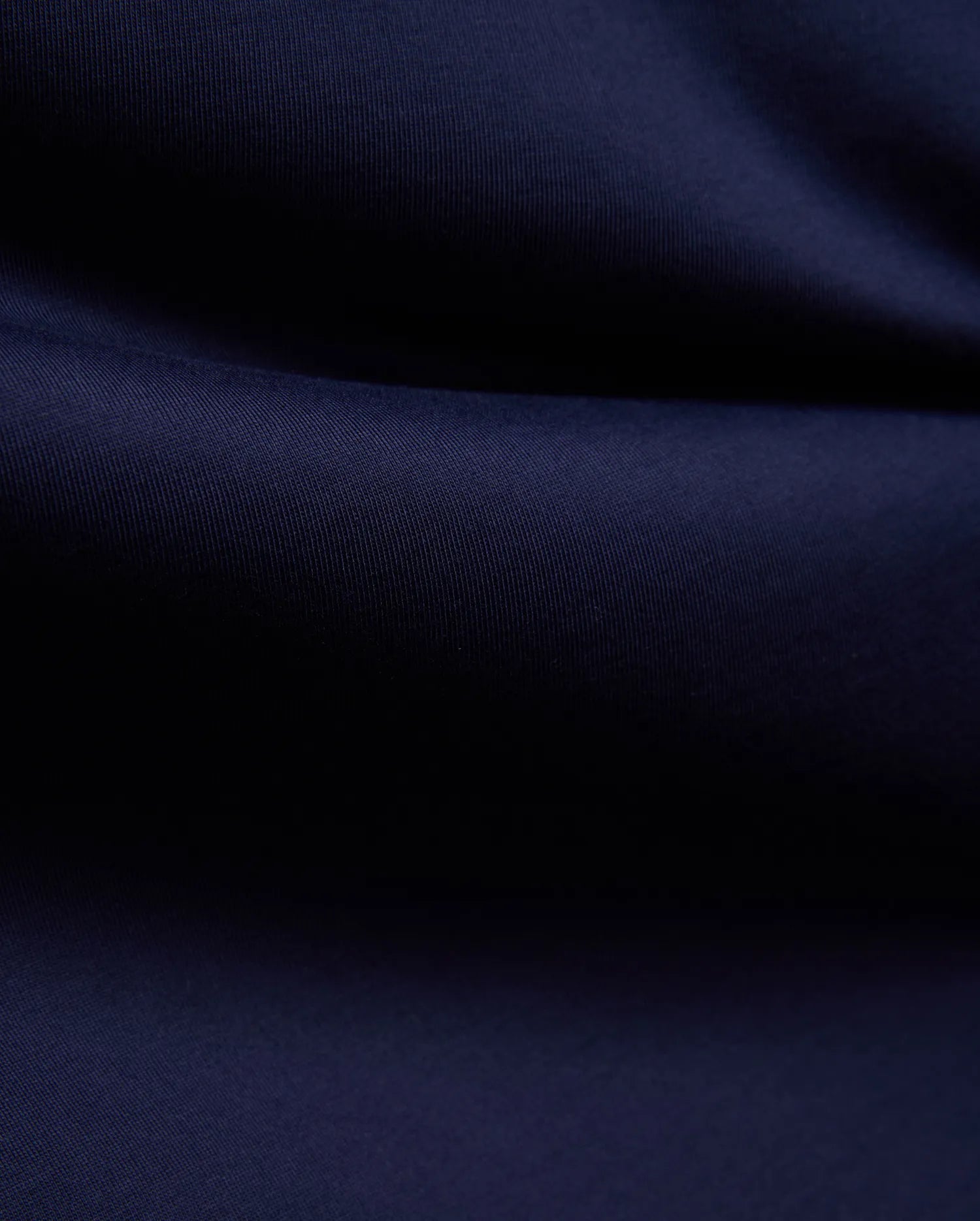 Mens John Graphic Tee, a premium Psycho Bunny dark navy blue t-shirt, showcasing its refined, soft, finely textured jersey knit fabric with elegant, flowing folds, perfect for refined streetwear.