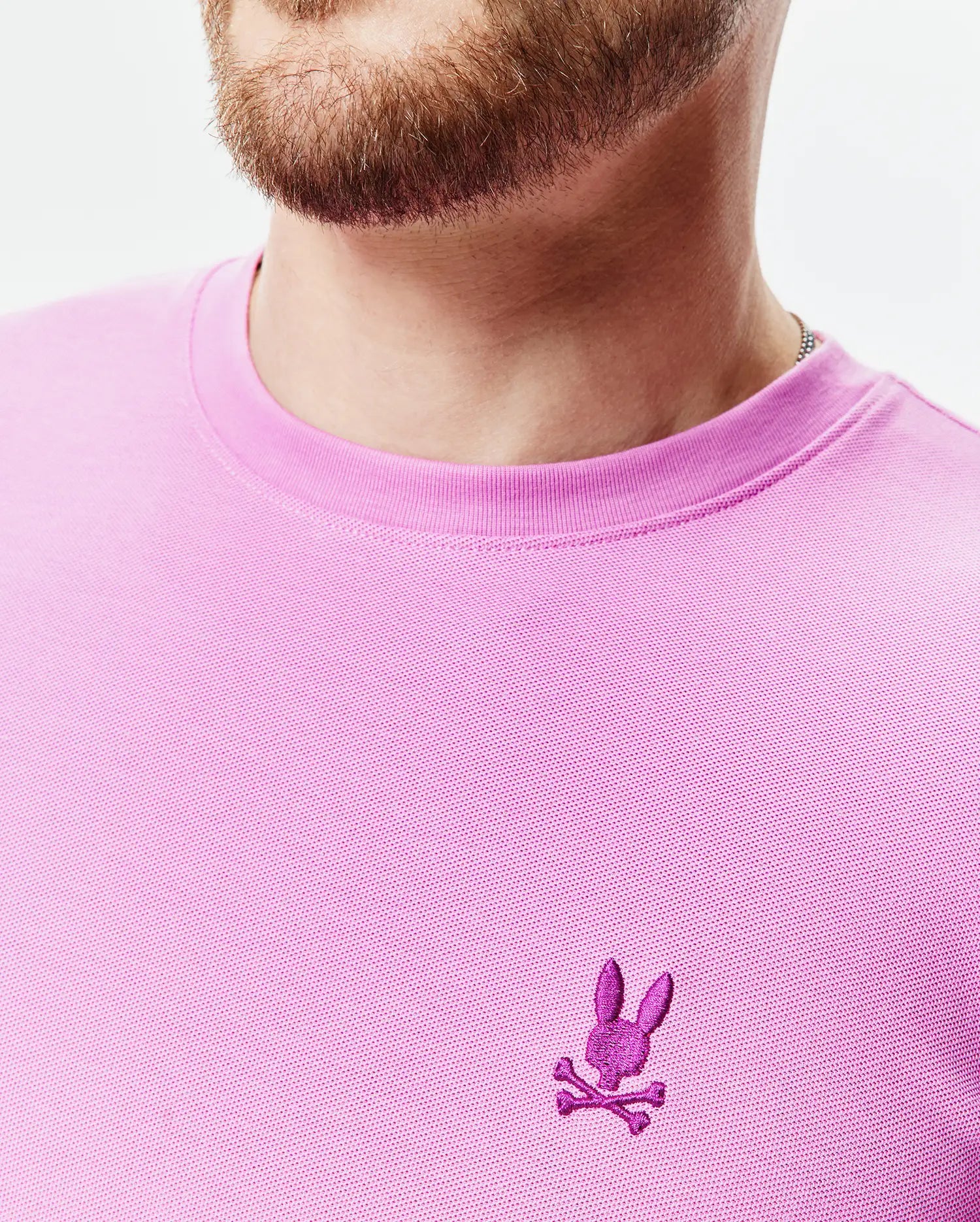 Mens Taylor Pique Tee in vibrant pink, classic fit, with a textured pique knit and a small, embroidered magenta Psycho Bunny skull logo on the left chest.