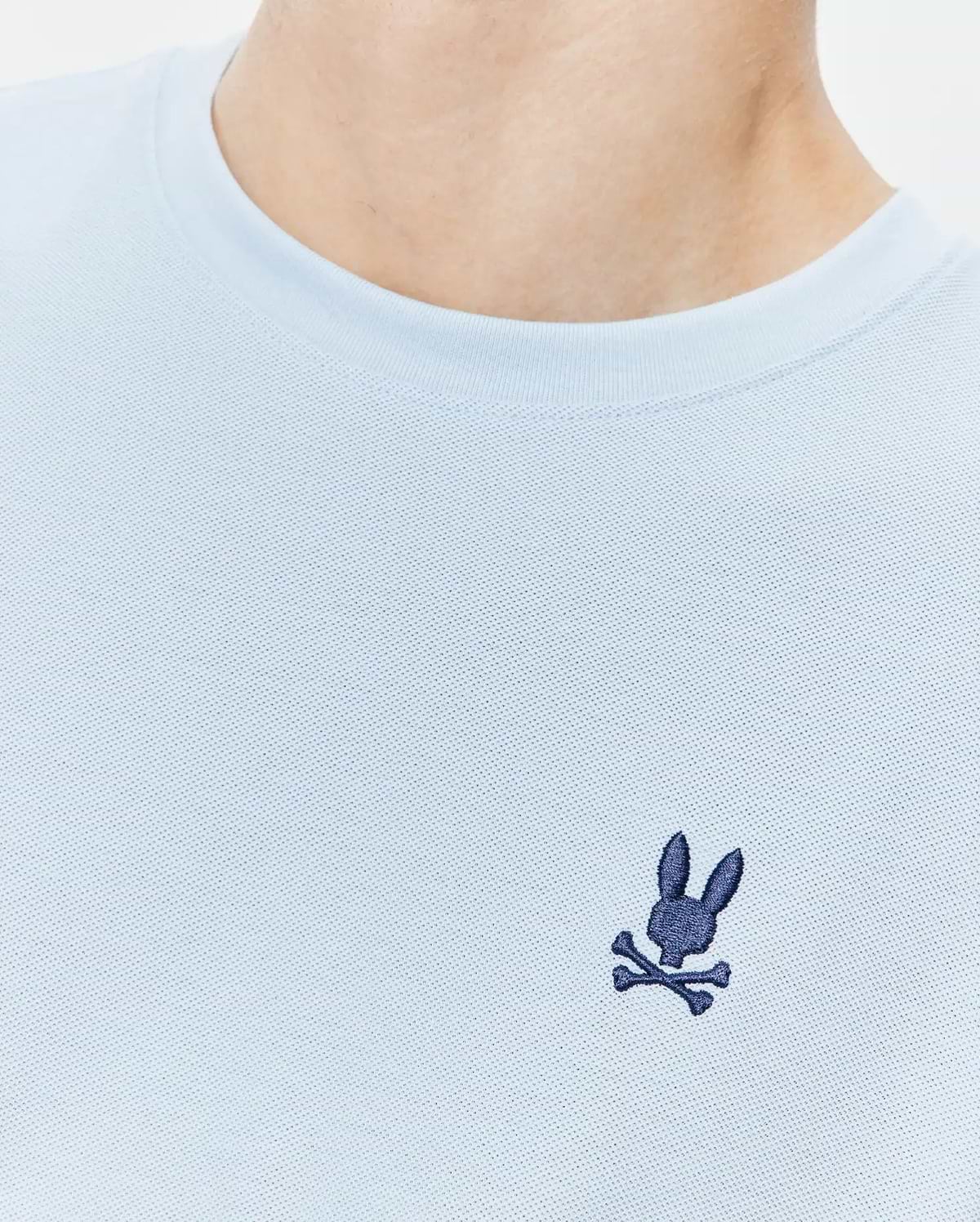 Light blue Mens Taylor Pique Tee with a classic fit, featuring a textured pique knit fabric and a small, embroidered dark blue Psycho Bunny skull logo on the left chest.