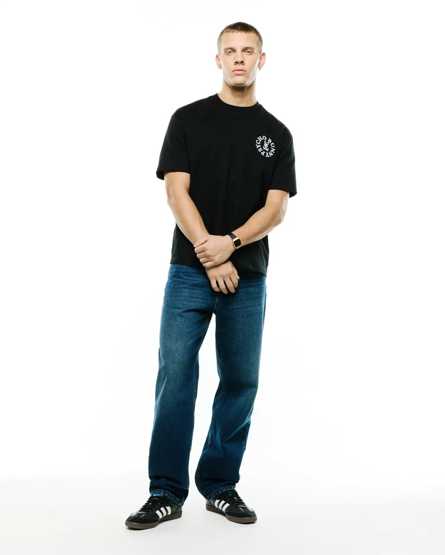 Mens Olek Relaxed Back Graphic Tee, a black relaxed fit soft jersey knit t-shirt featuring a small white circular Psycho Bunny skull logo with text on the left chest. (4)