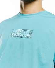 Men's Alfie Back Graphic Tee, aqua blue classic fit jersey knit with a chest graphic featuring three metallic silver Psycho Bunny skull logos on a textured rectangular background. (3)