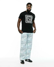 Black Men's Raj Wordmark Graphic Tee, classic fit, with a large white Psycho Bunny repeating wordmark and skull logo chest graphic. Paired with relaxed light blue and grey digital camo pants. (5)
