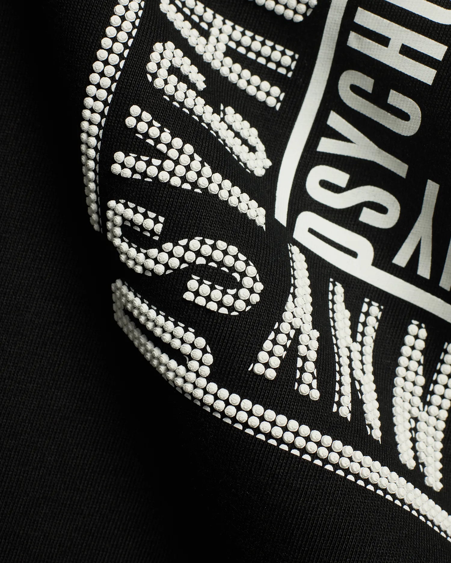 Men's Raj Wordmark Graphic Tee, a black jersey t-shirt featuring a prominent white graphic print with a unique textured dotted effect on parts of the Psycho Bunny wordmark. (6)
