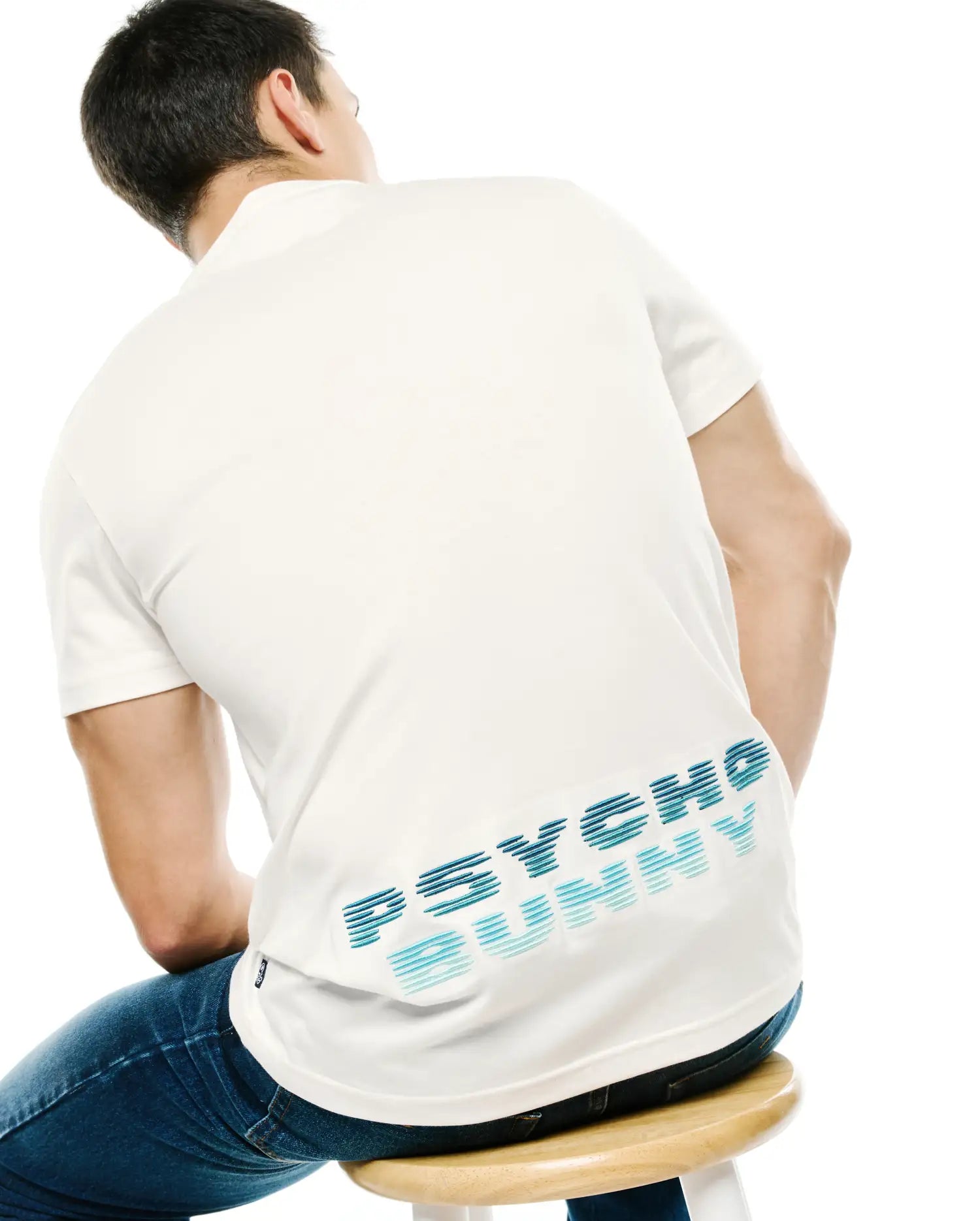 Men's Slade Bunny Graphic Tee. Cream classic fit pique polo with a large horizontal striped blue gradient PSYCHO BUNNY graphic on the lower back and a small brand tag on the side. (4)