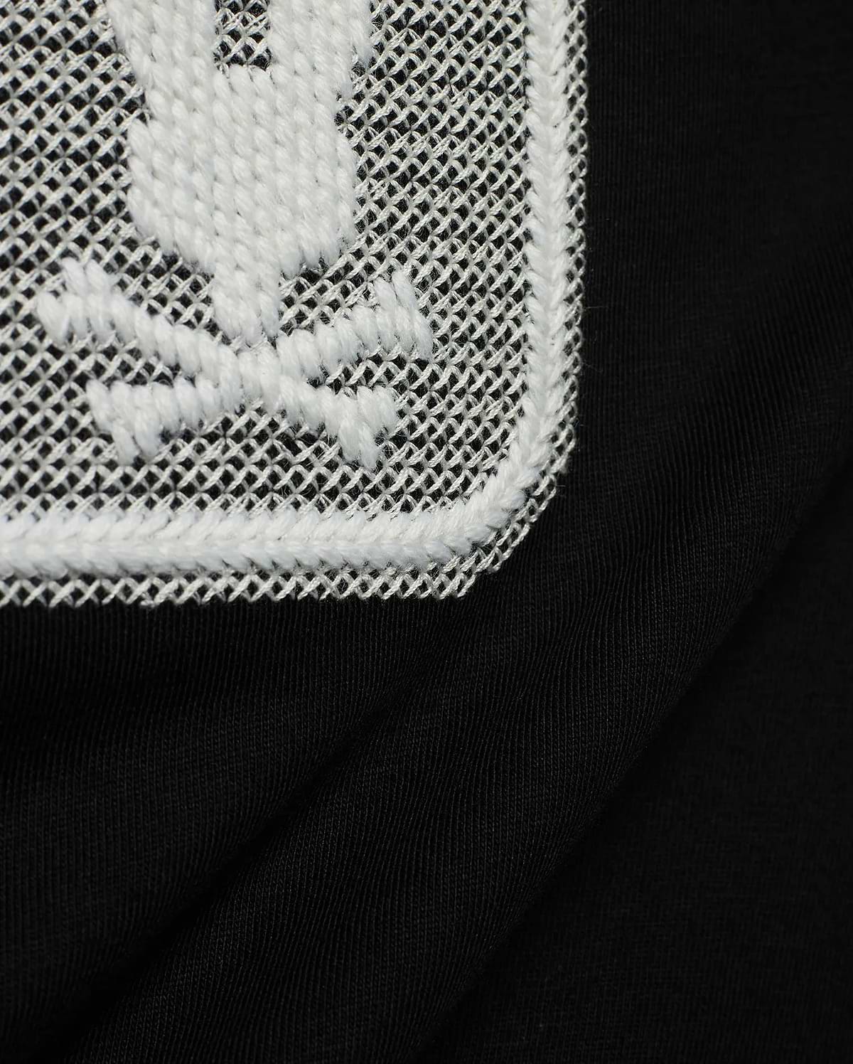 Men's Samson Wordmark Graphic Tee in black, crafted from soft jersey knit. Features a large, textured white embroidered Psycho Bunny skull logo on a white mesh patch. (6)