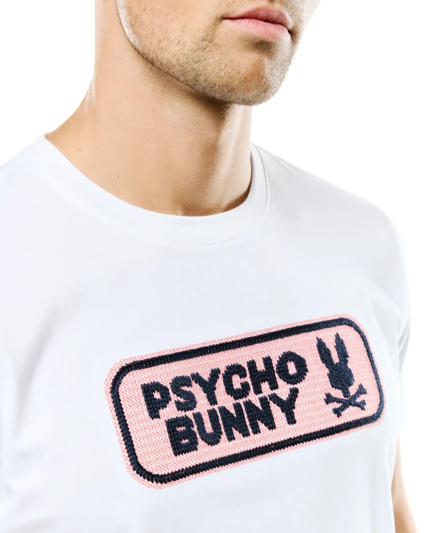 Men's Samson Wordmark Graphic Tee, white classic fit jersey t-shirt with a large central chest embroidered pink patch featuring the black Psycho Bunny wordmark and iconic bunny skull logo. (3)