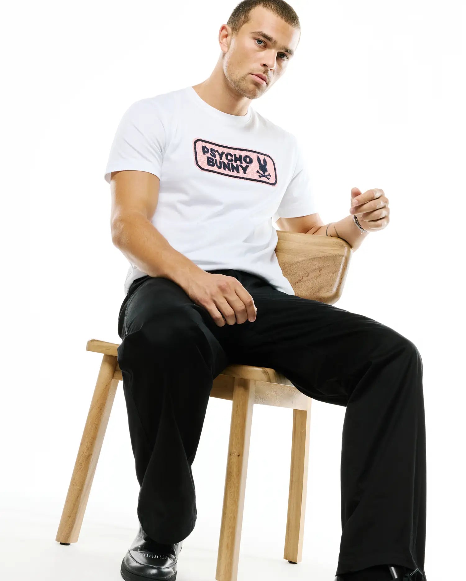 Men's Samson Wordmark Graphic Tee, a white classic fit jersey t-shirt featuring a prominent pink rectangular chest graphic with the black Psycho Bunny wordmark and skull logo. (2)