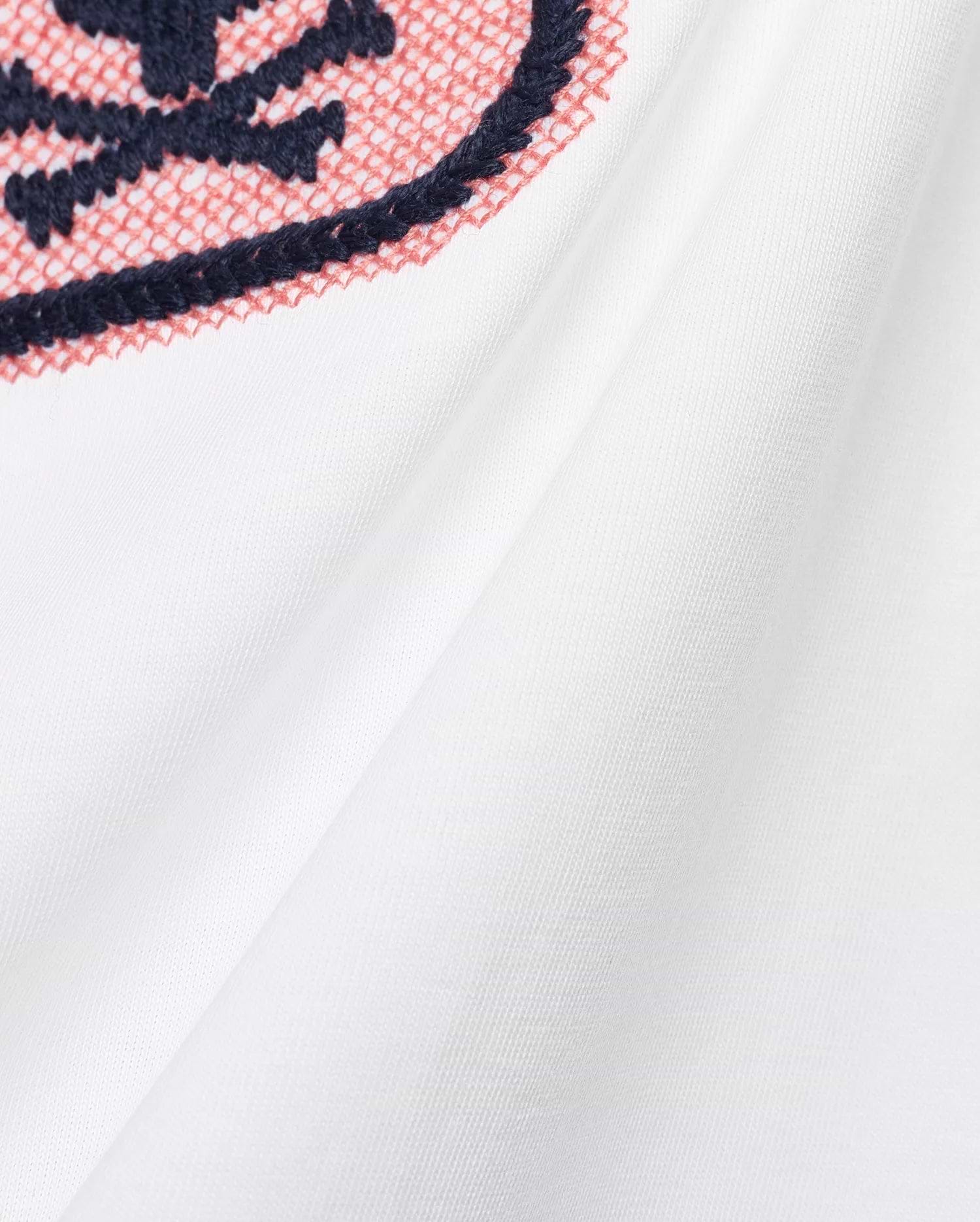 Men's Samson Wordmark Graphic Tee in white, featuring a prominent embroidered graphic with navy outline and coral cross-stitch fill on soft jersey fabric. (6)
