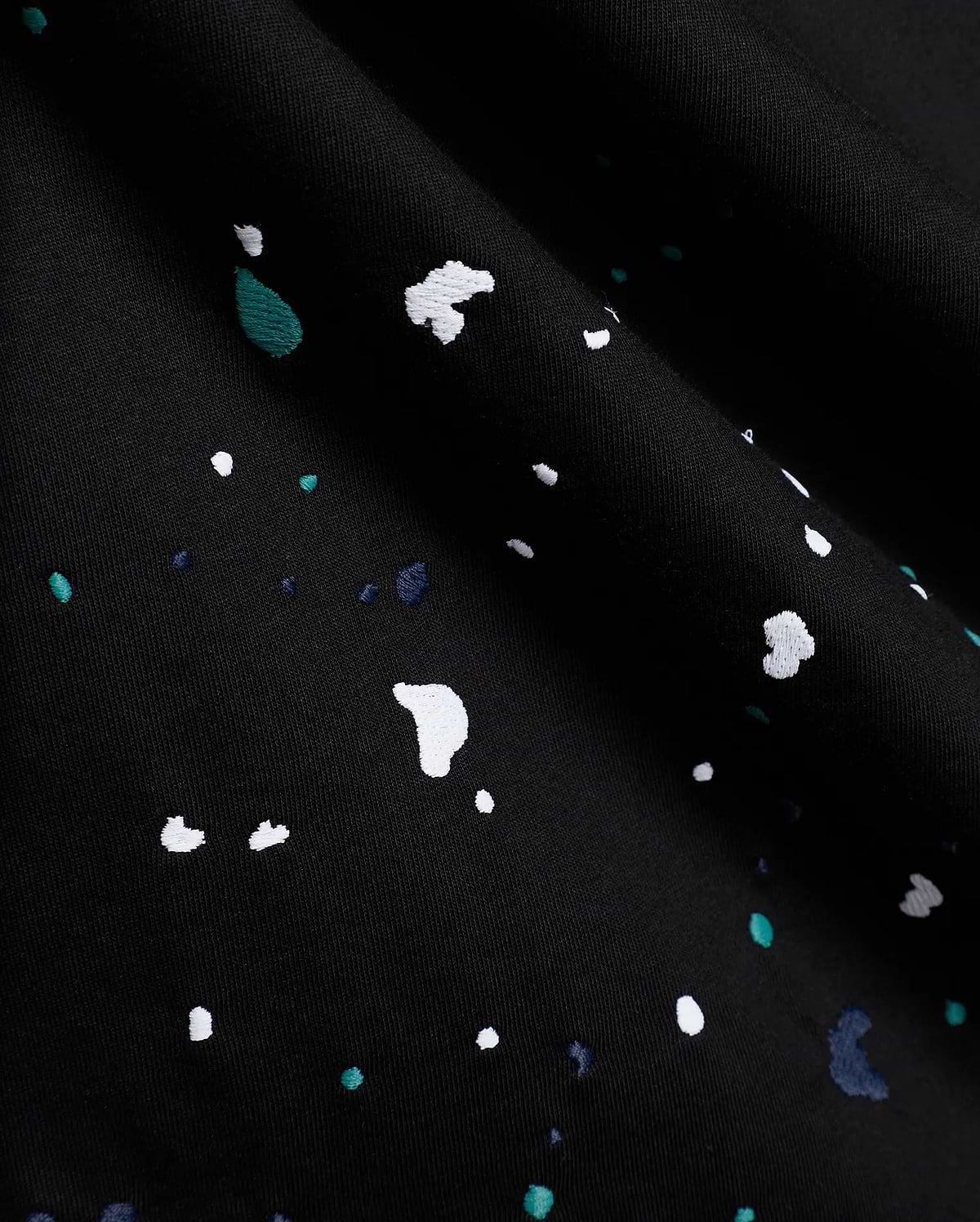 Black Mens Malcolm Graphic Tee crafted from smooth jersey knit fabric, adorned with an intricate embroidered paint splatter pattern in white, vibrant teal, and deep blue.