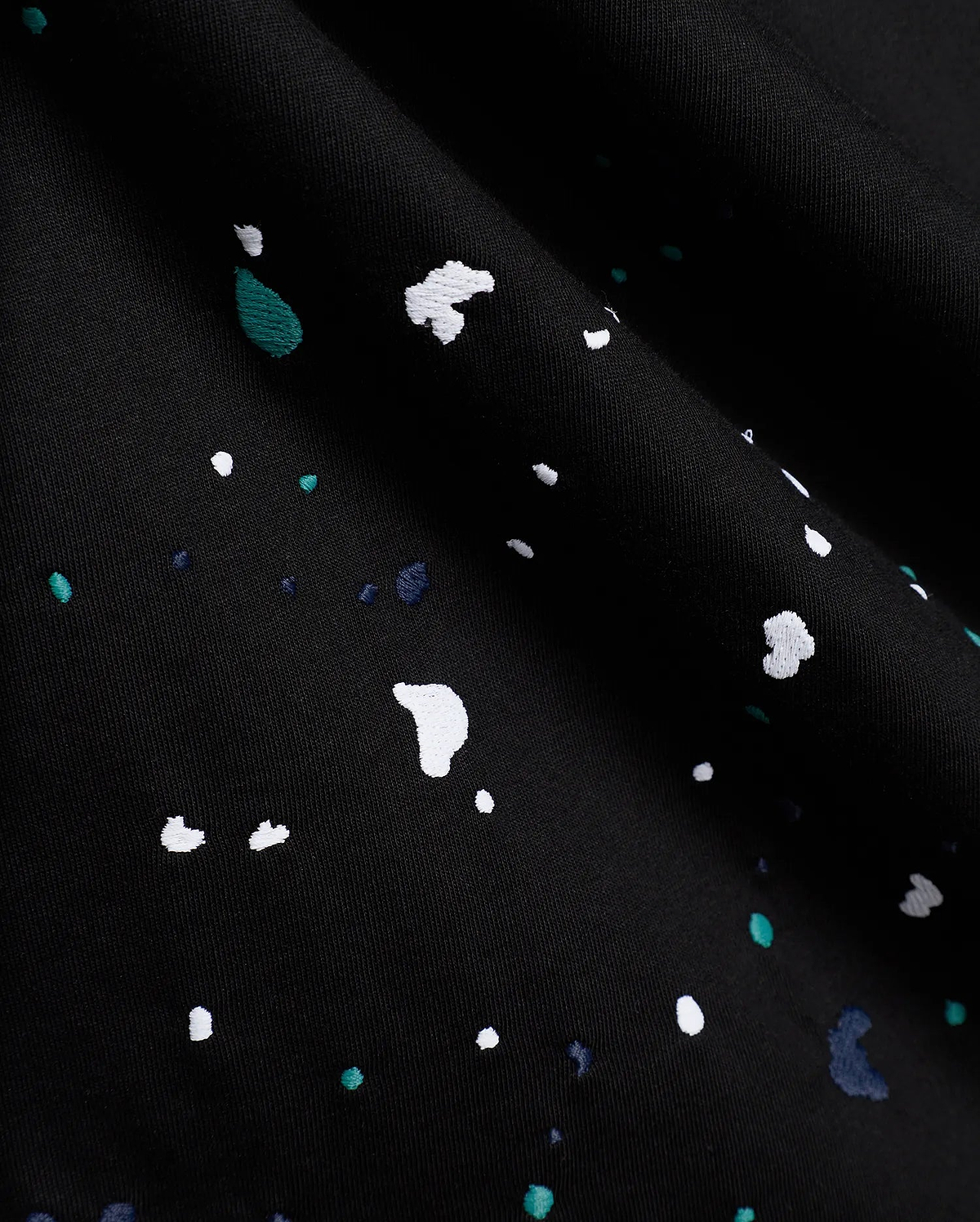 Black Mens Malcolm Graphic Tee crafted from smooth jersey knit fabric, adorned with an intricate embroidered paint splatter pattern in white, vibrant teal, and deep blue.