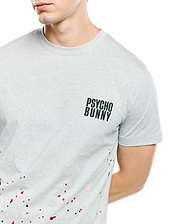 Mens Malcolm Graphic Tee, heather grey classic fit jersey t-shirt with small black Psycho Bunny text logo on left chest and vibrant black, red, and pink paint splatter graphic.