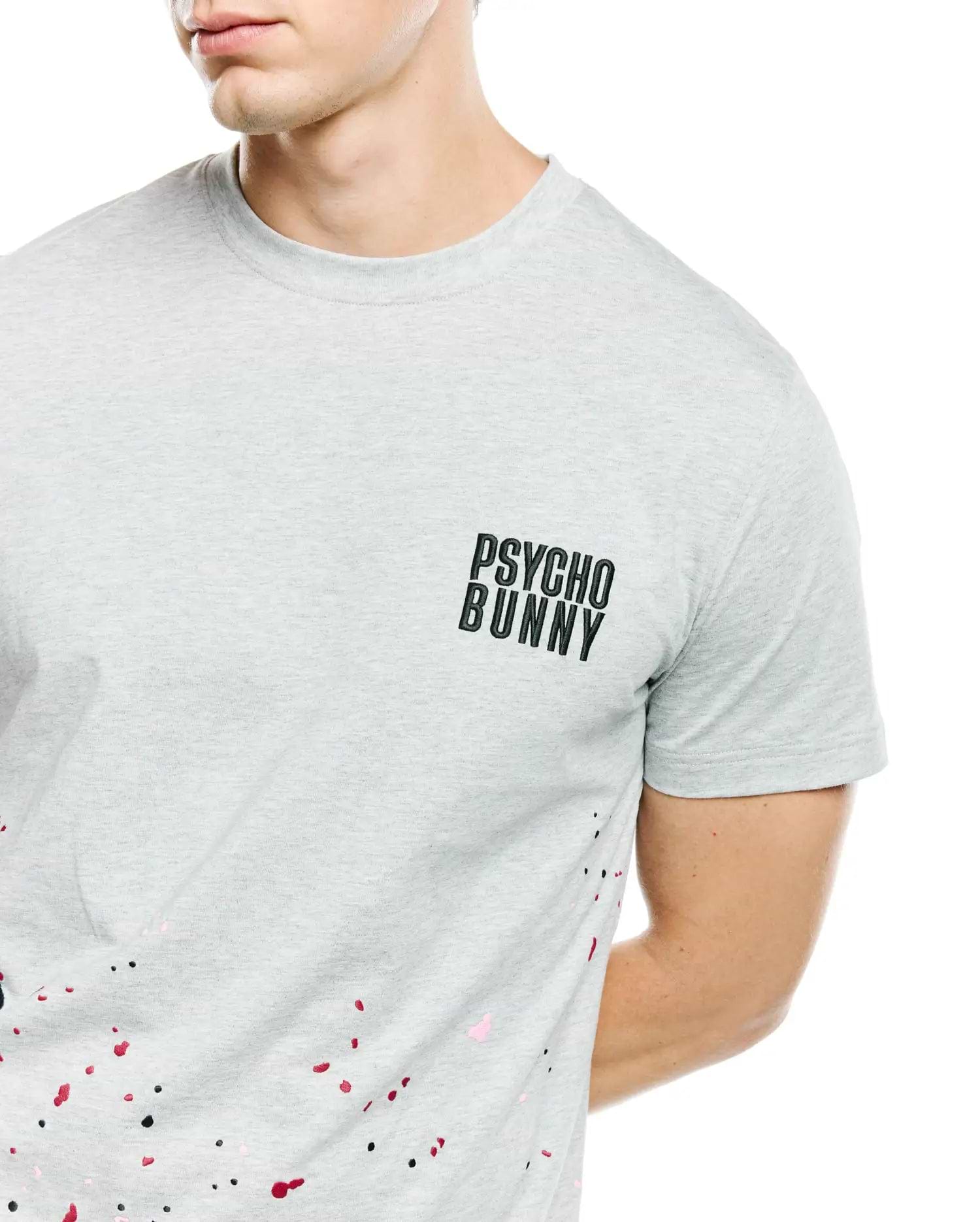 Mens Malcolm Graphic Tee, heather grey classic fit jersey t-shirt with small black Psycho Bunny text logo on left chest and vibrant black, red, and pink paint splatter graphic.