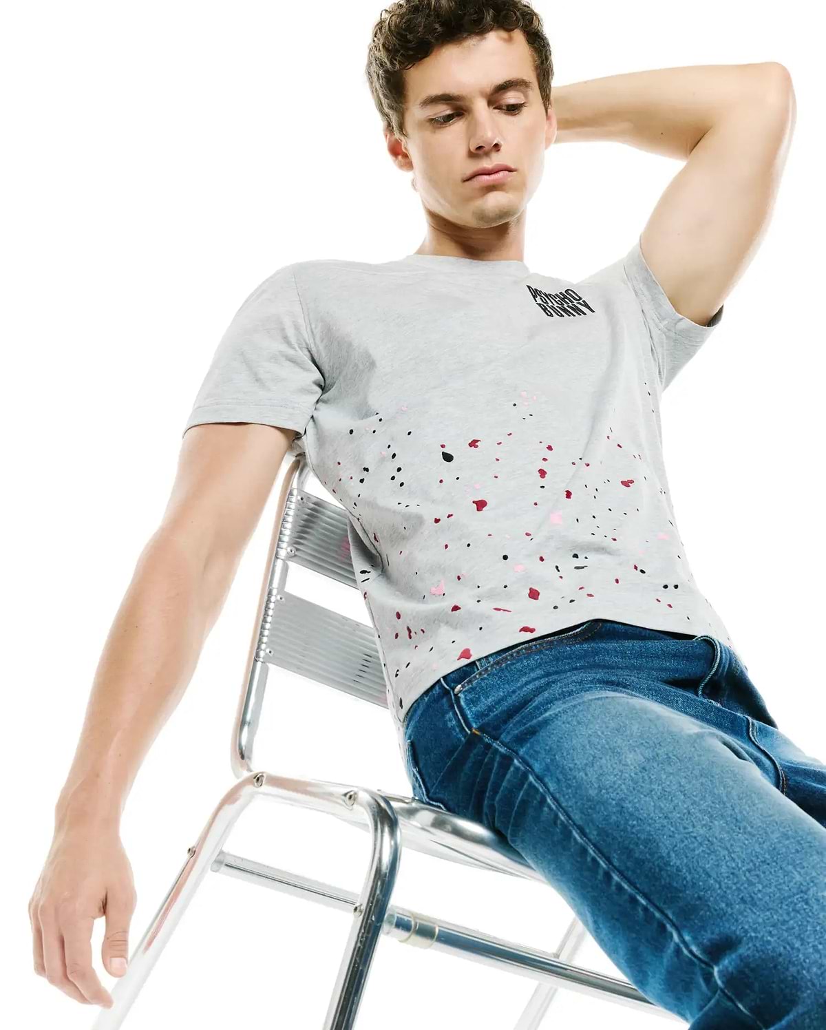 Mens Malcolm Graphic Tee, a classic fit heather grey jersey t-shirt featuring a small black Psycho Bunny text logo on the upper left chest and a vibrant red, black, and pink paint splatter graphic across the lower front.