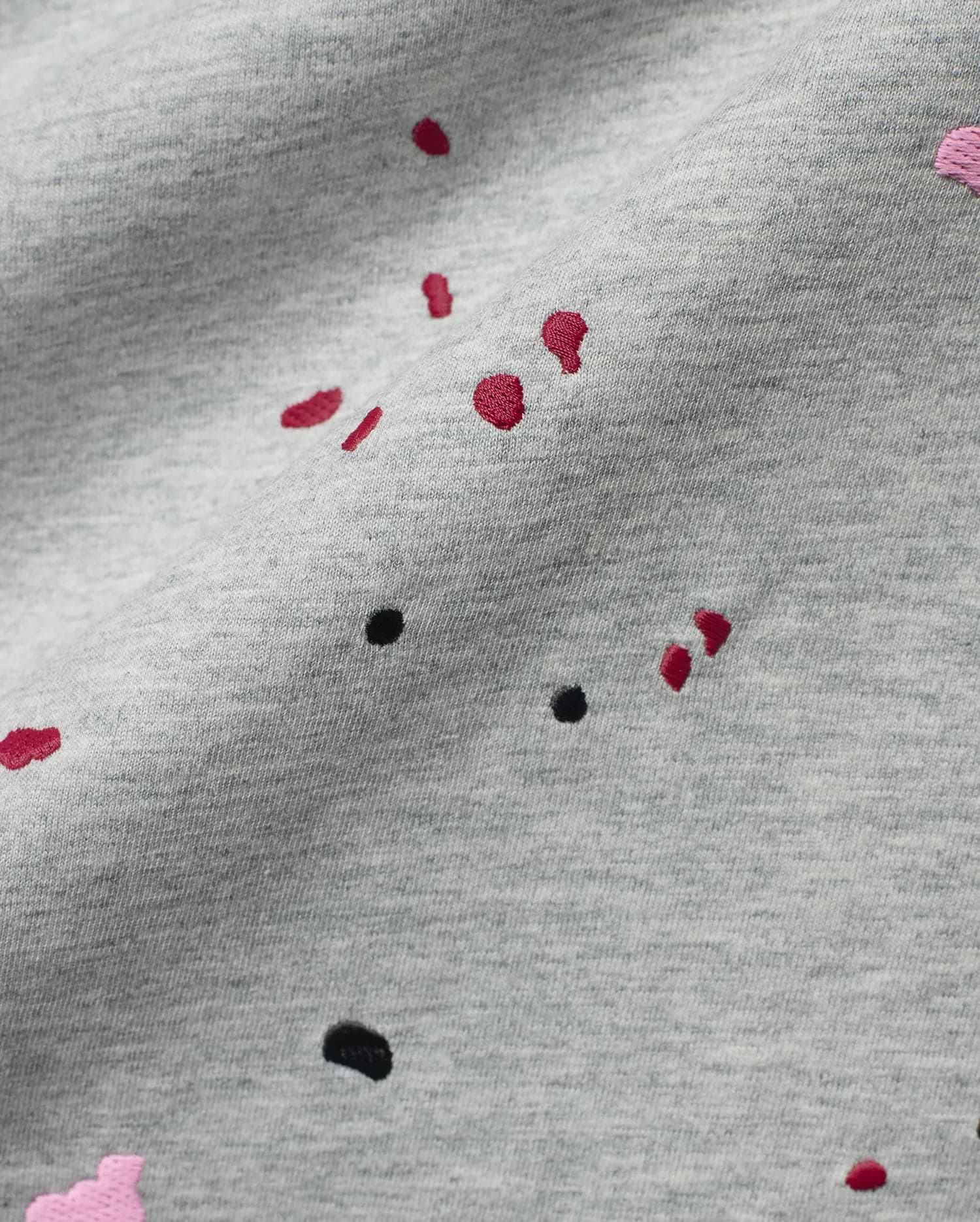 Mens Malcolm Graphic Tee, a heather grey jersey knit fabric detailed with embroidered red, black, and pink paint splatter graphics for a bold, refined streetwear look.