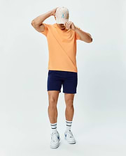 Mens Dash Bunny Sport Tee in peach performance jersey, classic fit, with a small embroidered Psycho Bunny logo on the chest, paired with navy athletic shorts, a striped cap, and white Psycho Bunny socks. (4)