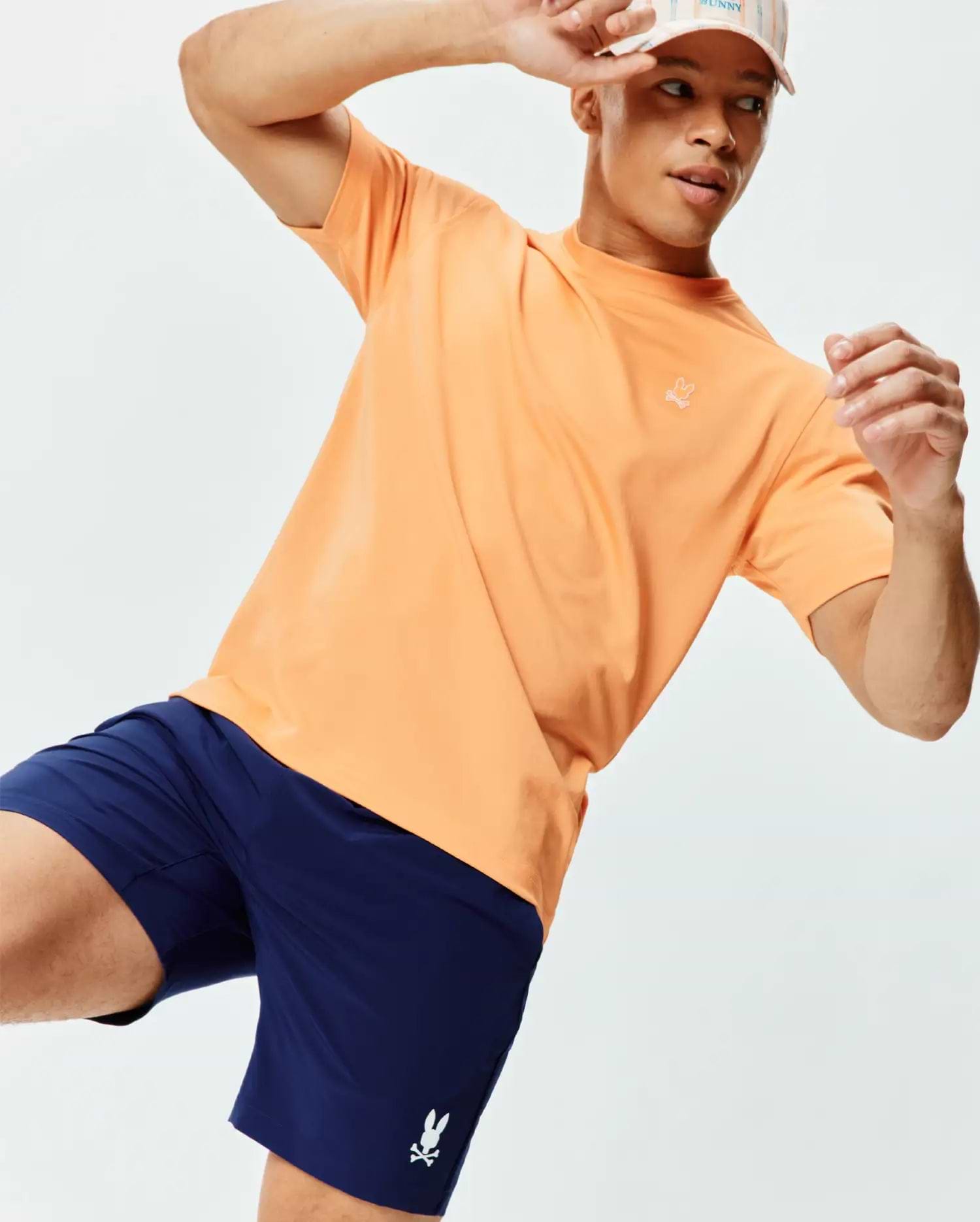 Mens Dash Bunny Sport Tee, a relaxed peach jersey t-shirt with a small white embroidered bunny skull logo on the left chest, paired with navy athletic shorts featuring a white bunny skull logo. (3)