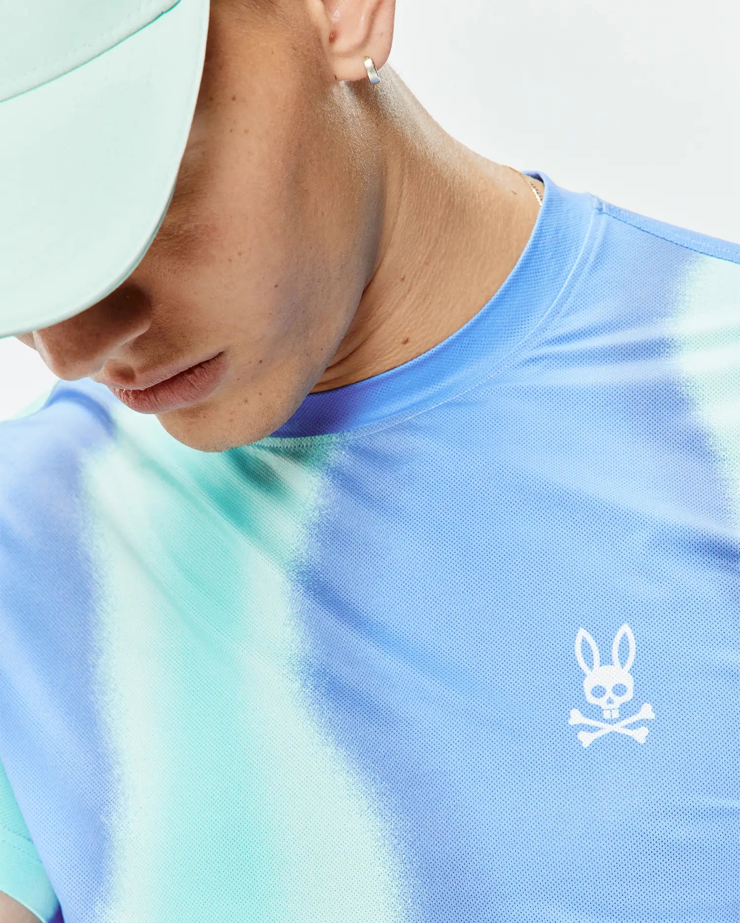 Mens Blaze Sport Tee featuring a vibrant blue, light blue, and mint green tie-dye pattern on a mesh performance fabric, with a small white embroidered Psycho Bunny skull logo on the left chest.