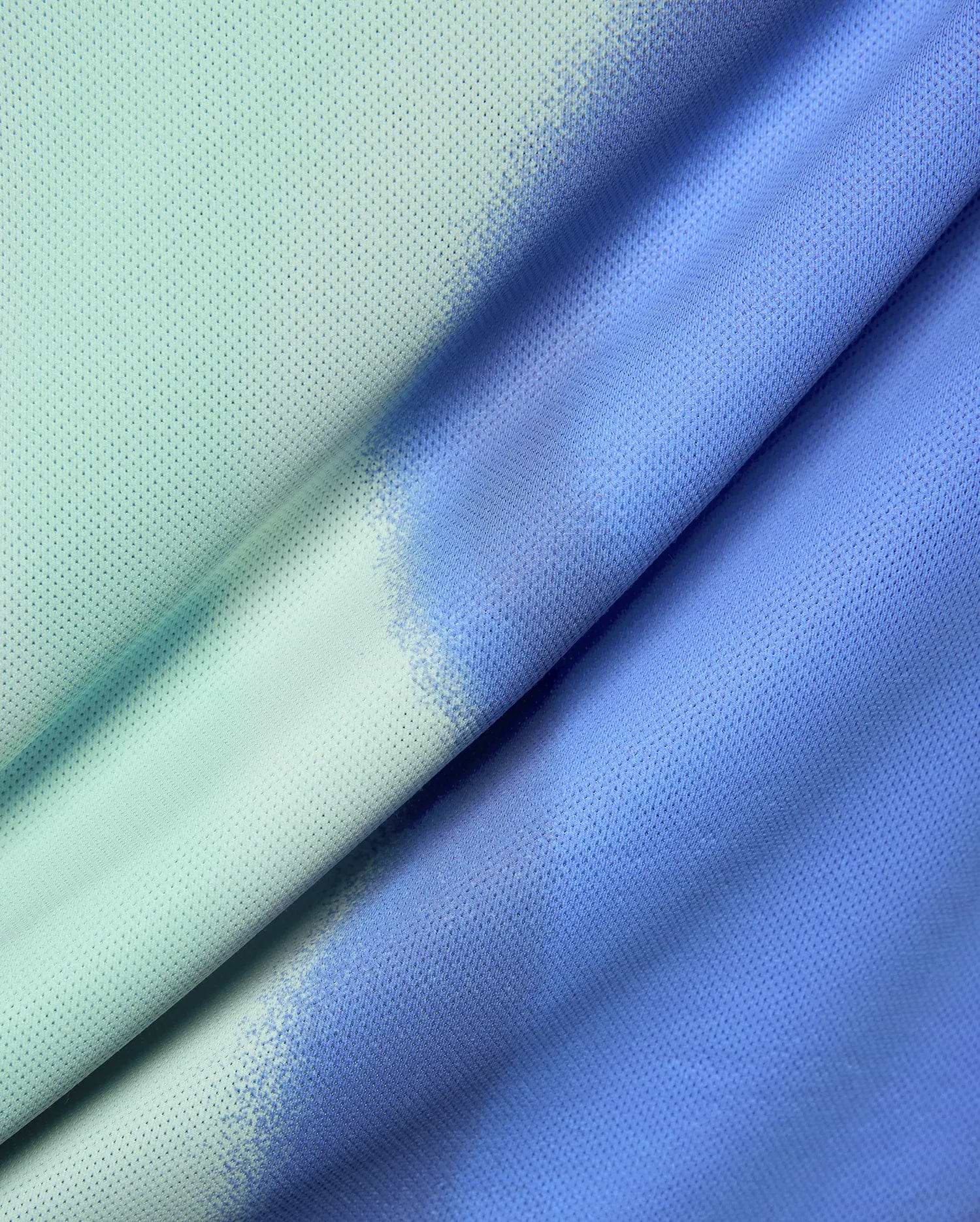 Mens Blaze Sport Tee featuring a breathable mesh fabric with a unique distressed ombre gradient, transitioning from a light mint green to a vibrant periwinkle blue.