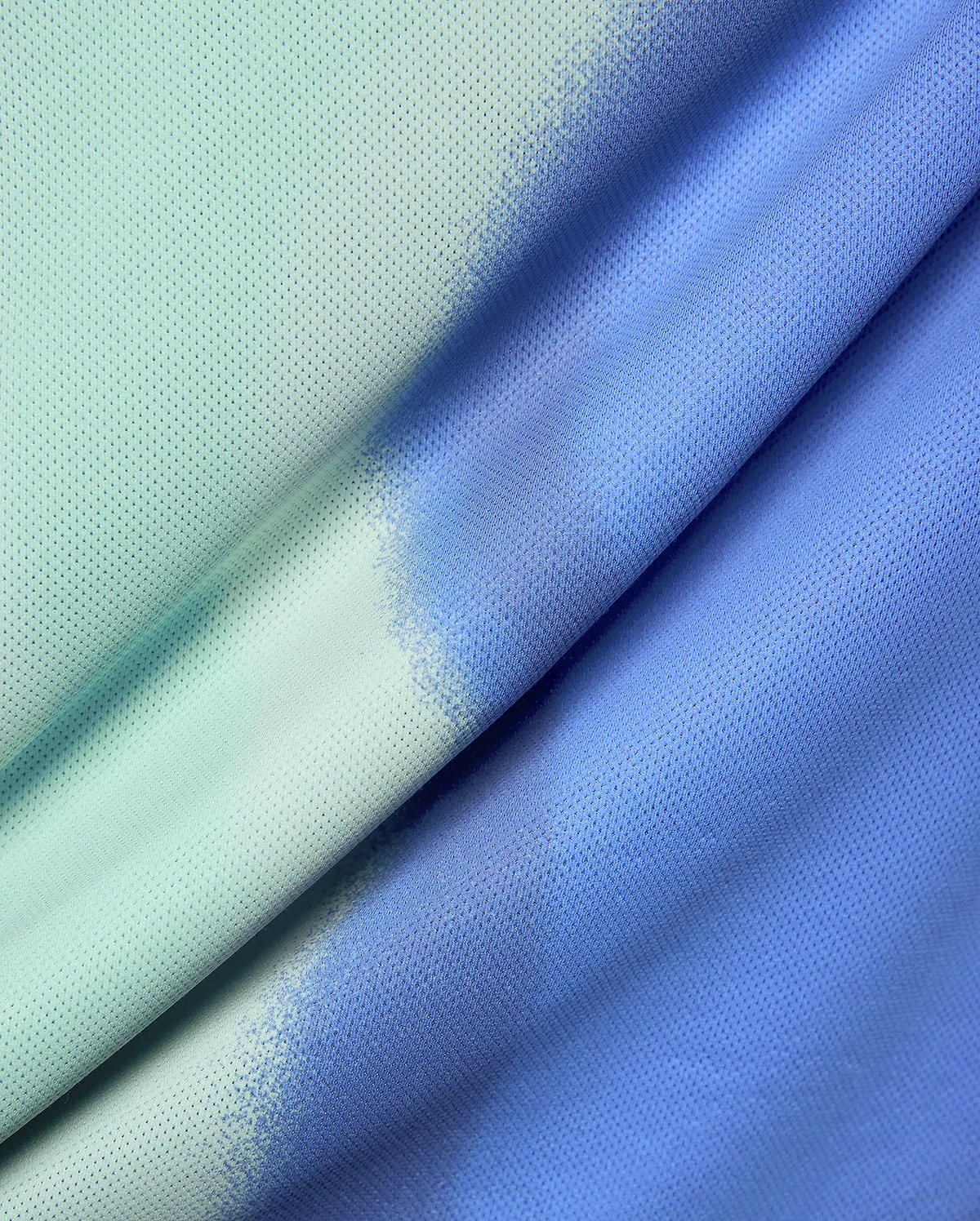 Mens Blaze Sport Tee featuring a breathable mesh fabric with a unique distressed ombre gradient, transitioning from a light mint green to a vibrant periwinkle blue.